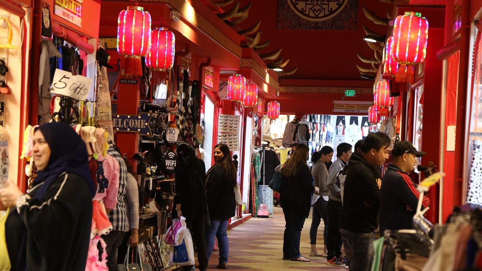 Shoppers in a lantern-lit pavilion lane at Global Village, Dubai